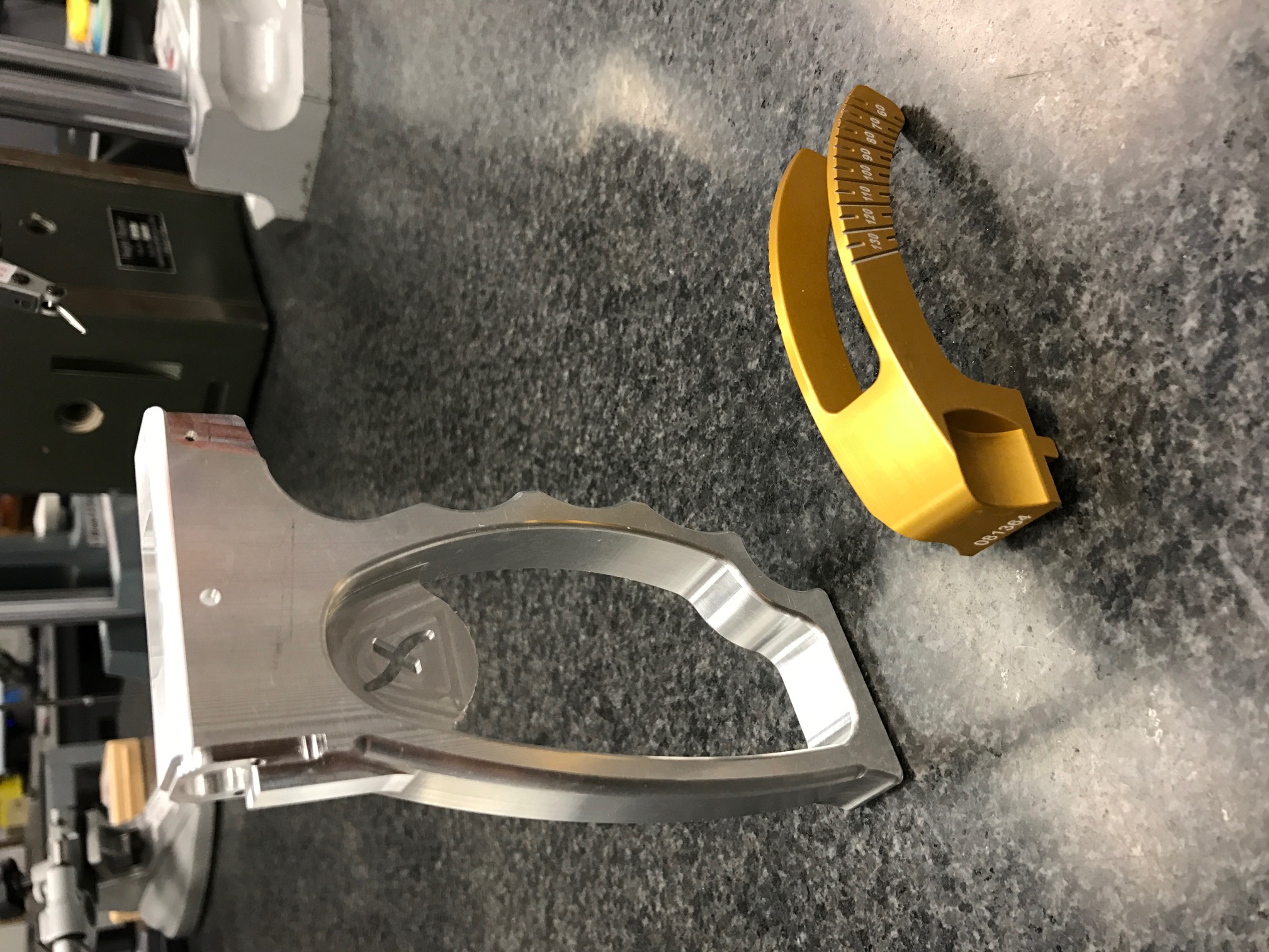 Two precision-machined aluminum components on an inspection table